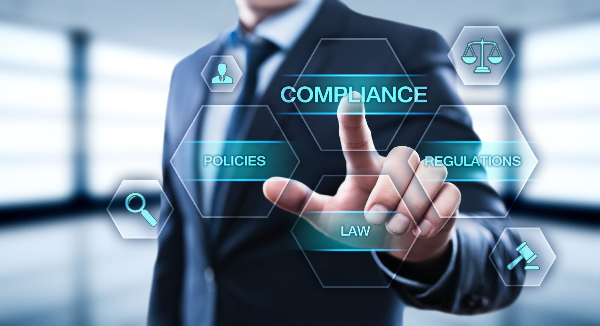 Four words—compliance, policies, regulations. law—appear on a virtual screen in front of a business person who is reaching out to select "compliance"